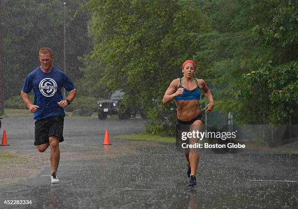 Harry Palley and Rachel Martinez, both instructors at CrossFit New England of Natick, Mass., train under the rain. Martinez is getting ready to...