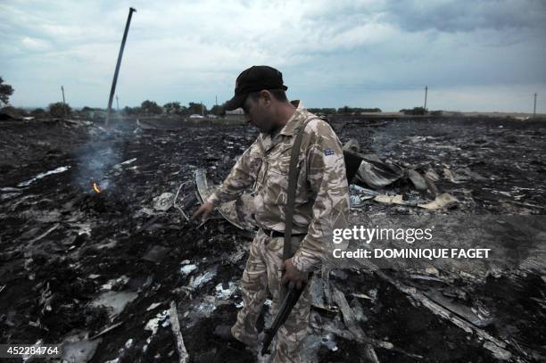 Man wearing military fatigues points to the wreckage of the malaysian airliner carrying 295 people from Amsterdam to Kuala Lumpur after it crashed,...