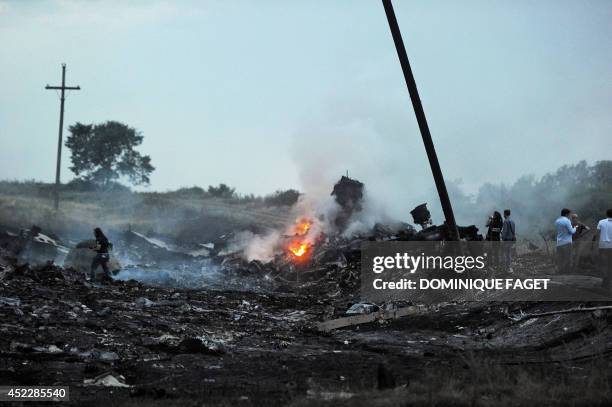 People stand, on July 17 amongst the wreckages of the malaysian airliner carrying 295 people from Amsterdam to Kuala Lumpur after it crashed, near...