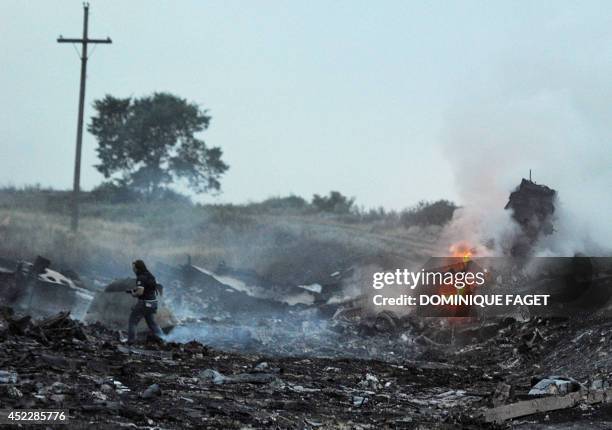 People stand, on July 17 amongst the wreckages of the malaysian airliner carrying 295 people from Amsterdam to Kuala Lumpur after it crashed, near...