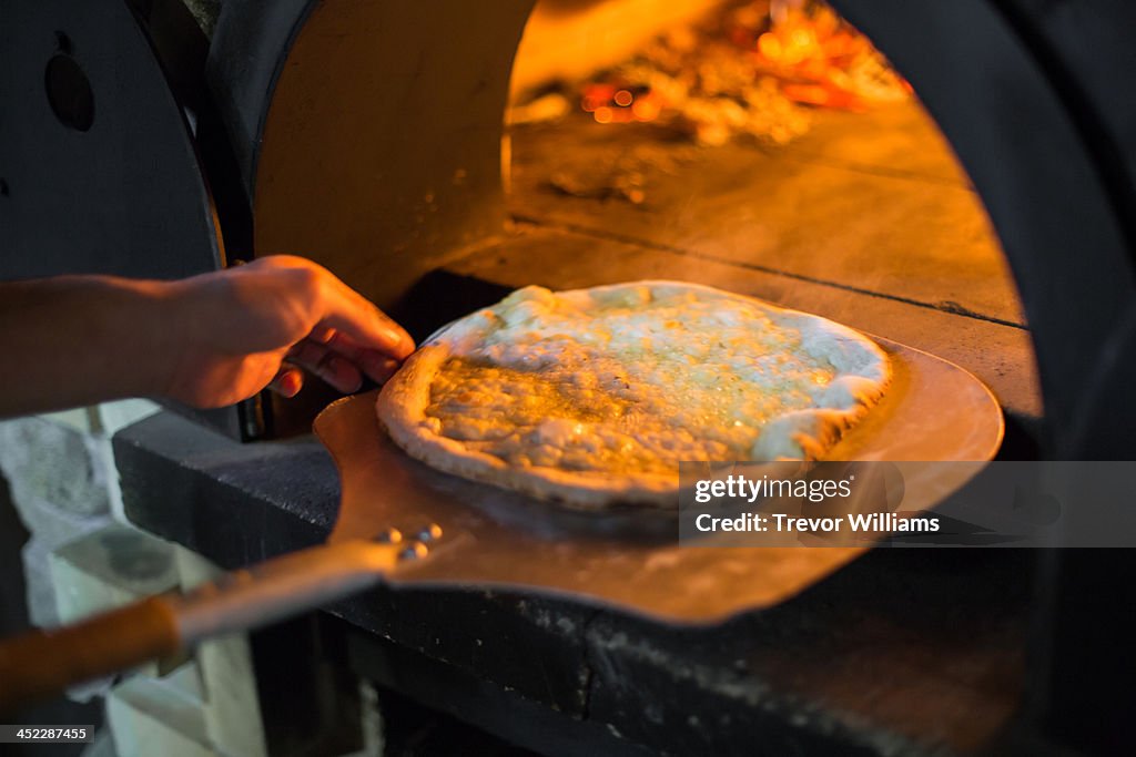 A pizza coming out of a stone oven