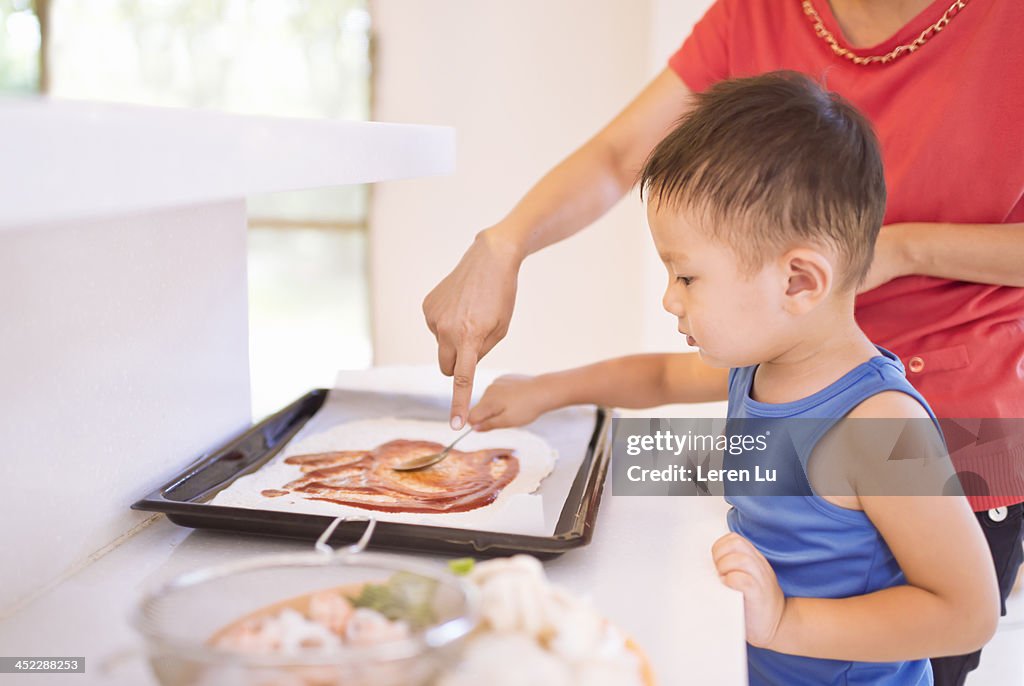 Kid and mother making pizza at home