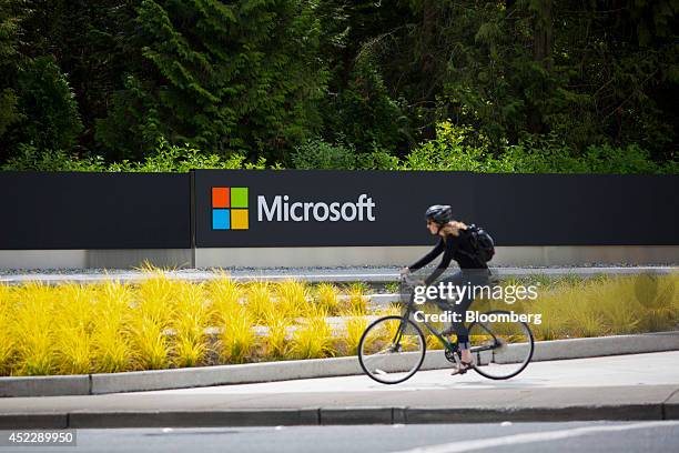 Woman rides a bicycle past a Microsoft Corp. Sign on the company's main campus in Redmond, Washington, U.S., on Wednesday, July 17, 2014. Microsoft...