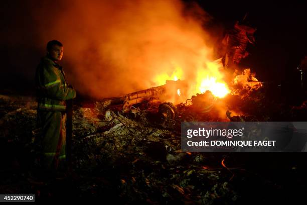 Firefighter stands as flames burst amongst the wreckages of the malaysian airliner carrying 298 people from Amsterdam to Kuala Lumpur after it...