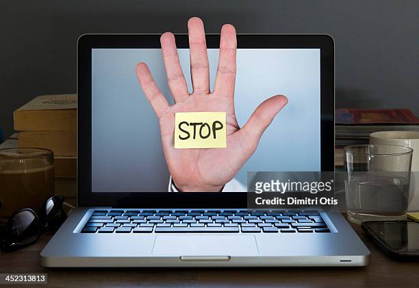 stop hand appearing out of laptop computer screen - stop ストックフォトと画像
