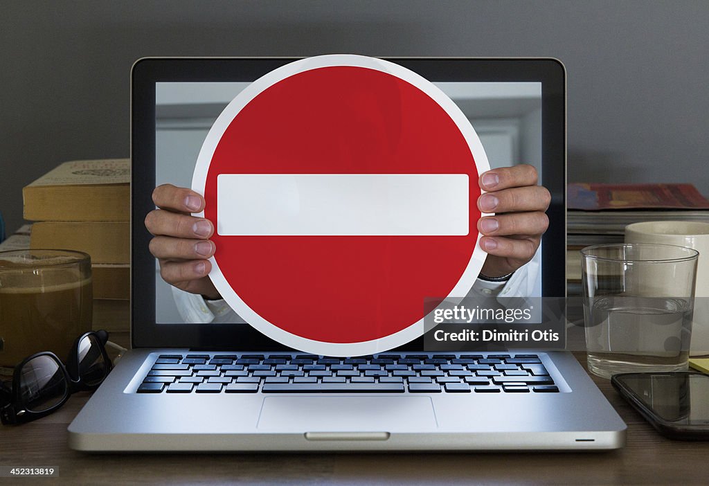 No entry sign appearing out of laptop computer