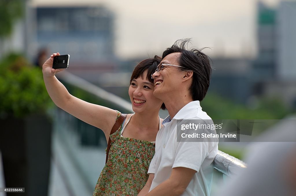 A young Chinese couple taking photos in Hong Kong with an...