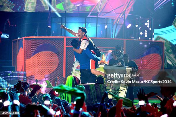 Host Michael Strahan and Ricardo Jacobo Jr., winner of the $50,000 Kids Choice Sports Half-Court Shot Contest embrace onstage during Nickelodeon...