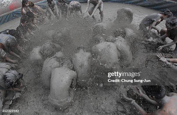 Festival-goers wrestle in the mud during the annual Boryeong Mud Festival at Daecheon Beach on July 18, 2014 in Boryeong, South Korea. The mud, which...