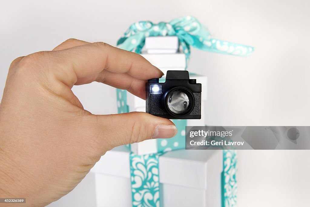 Woman holding a small camera in front of gifts