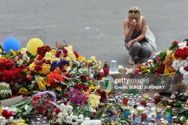 Woman crosses herself as people lay flowers and light candles in front of the Embassy of the Netherlands in Kiev on July 18 to commemorate passengers...