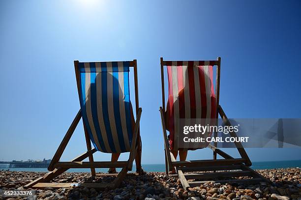 People relax in deck chairs on the beach in Brighton on July 18 as parts of the country were expected to experience the hottest day of the year so...