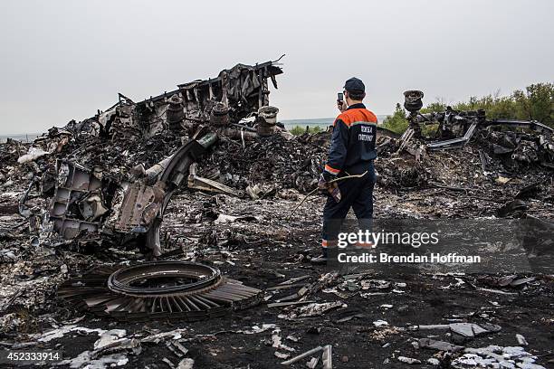 An emergency services worker photographs debris from an Malaysia Airlines plane crash on July 18, 2014 in Grabovka, Ukraine. Malaysia Airlines flight...