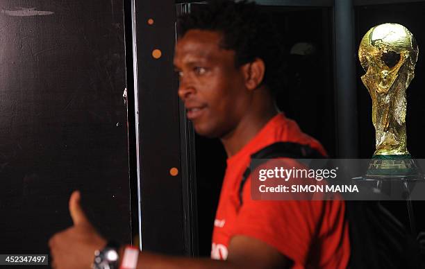 Man gestures as he poses for a photograph next to the FIFA World Cup trophy on November 28, 2013 during a public viewing in Nairobi, a day after its...