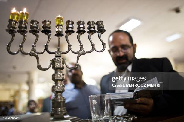 Iranian Jewish Rabbi Younes Hamami Lalehzar reads prayers after lighting candles to mark Hanukkah, the festival of lights, at Abrishami synagogue in...