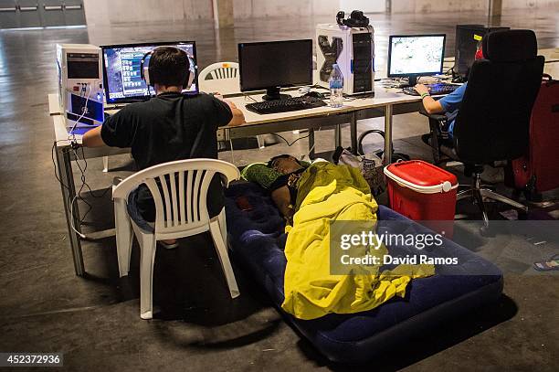 Participant spleeps after spending the night at the LAN area as his mates keep on playing on their computers during the DreamHack Valencia 2014 on...