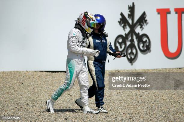 Lewis Hamilton of Great Britain and Mercedes GP speaks to the doctor as he leaves his car after crashing during qualifying ahead of the German Grand...