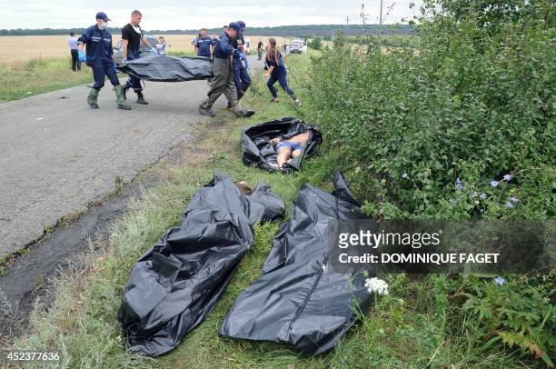 Ukrainian rescue workers carry the body of a victim on a stretcher as others bodies of victims lay on the ground prior to be collected at the site of...