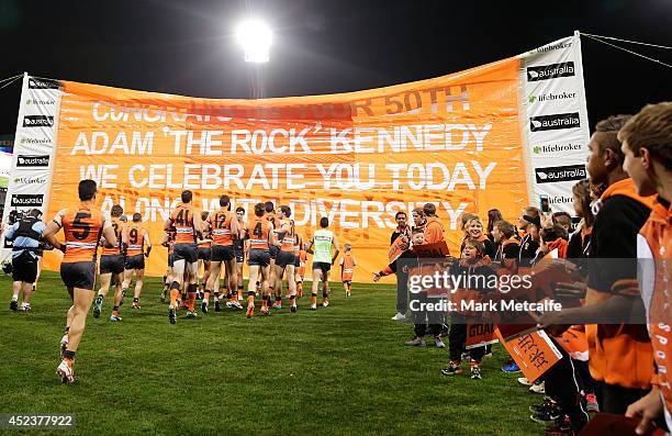 Giants players run through a banner celebrating Adam Kennedy's 50th game before the round 18 AFL match between the Greater Western Sydney Giants and...