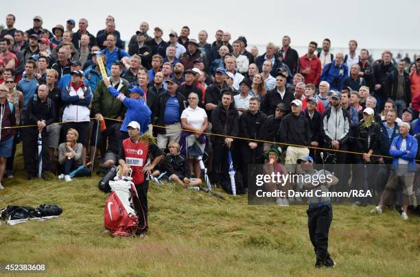 Rory McIlroy of Northern Ireland hits his second shot on the 12th hole as a gallery of fans look on during the third round of The 143rd Open...