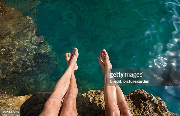 Couple's Legs Above Turquoise Ocean