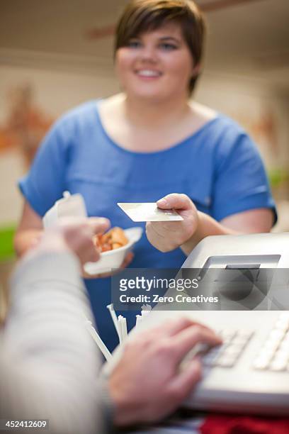 young woman paying for takeaway order in cafe - chubby credit fotografías e imágenes de stock