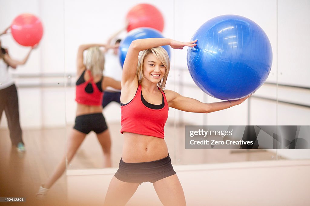 Young woman holding exercise ball in aerobics class