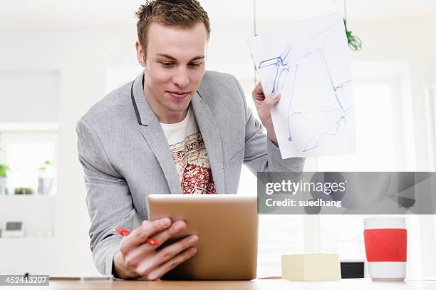 man holding up sketch in front of digital tablet - bavarian man in front of house stockfoto's en -beelden