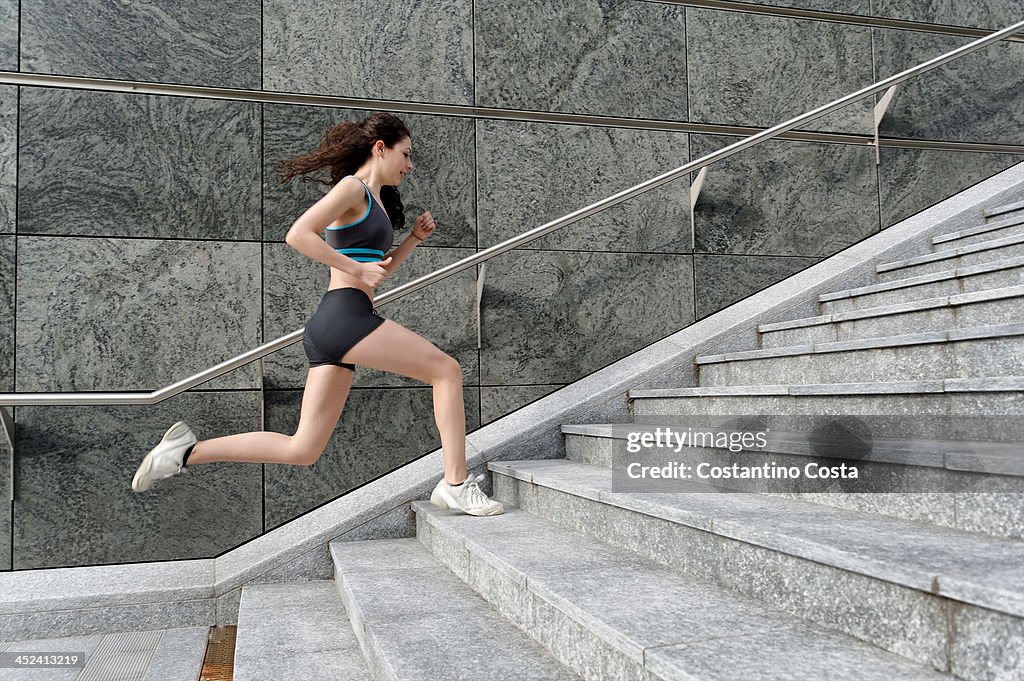 Young woman running up stairway