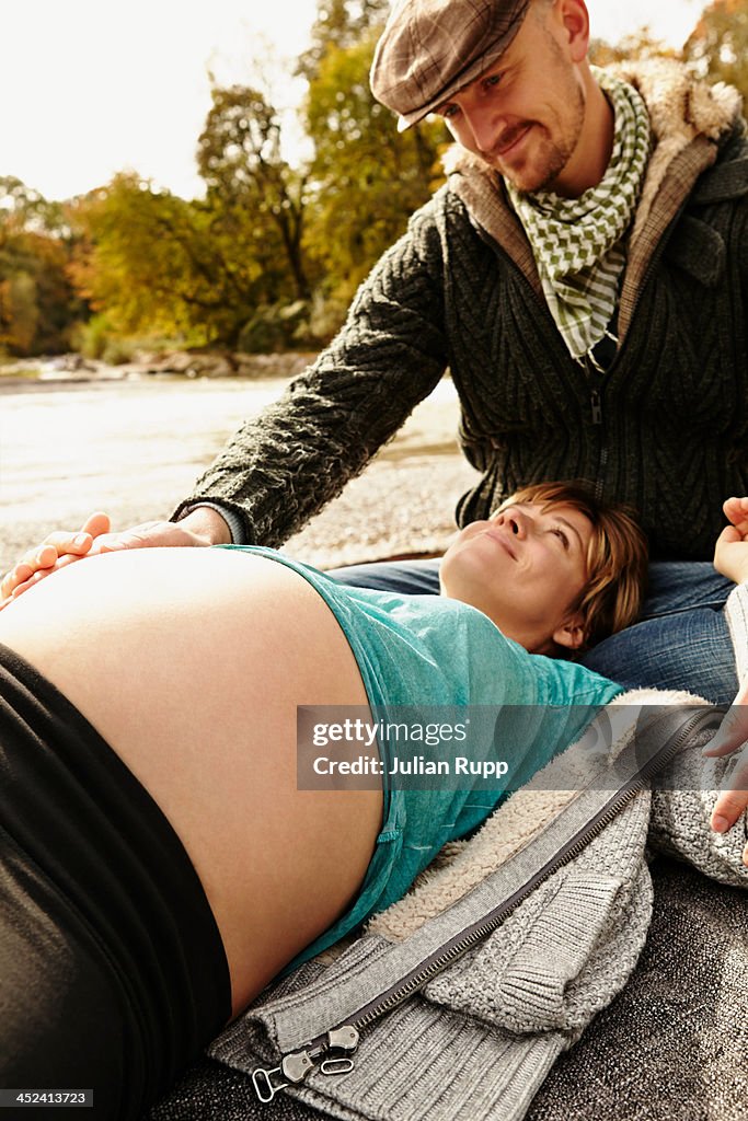 Pregnant woman lying beside river