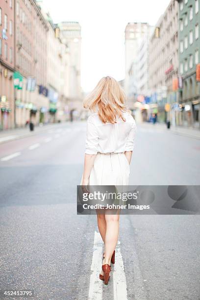 woman walking on street, rear view - skirt stock pictures, royalty-free photos & images