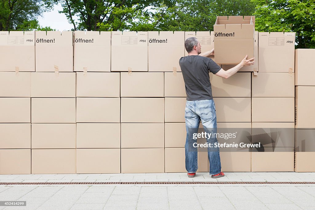 Man building wall of cardboard boxes