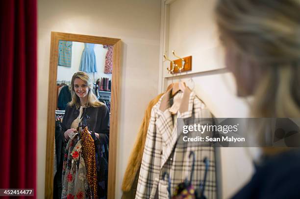 woman taking clothes into fitting room - anprobekabine stock-fotos und bilder