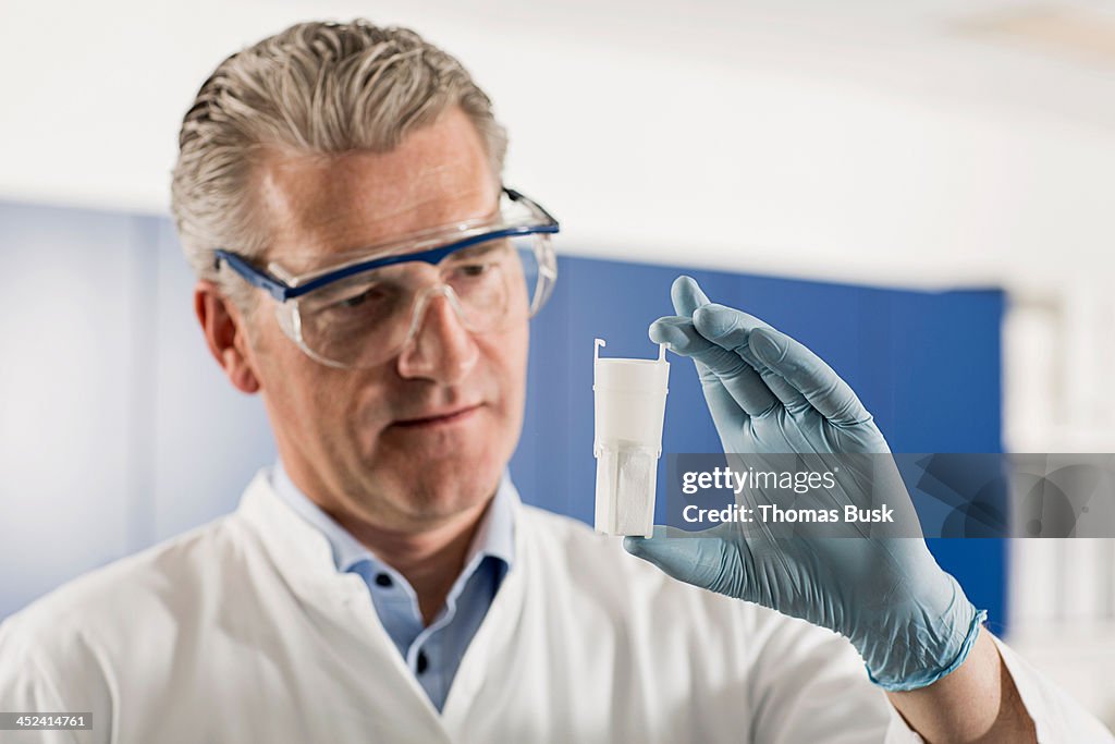 Scientist looking at container in laboratory