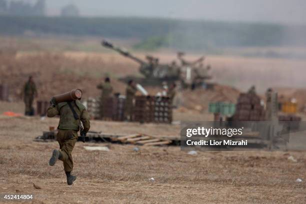 An Israeli soldier runs with shell next to artillery cannons on July 20, 2014 at the Israeli-Gaza border. Protests have taken place all around the...