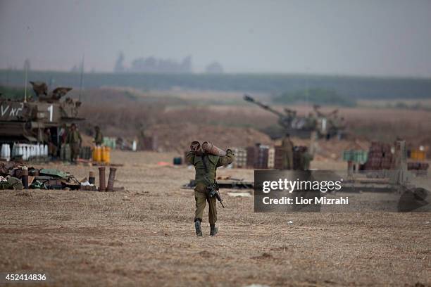 An Israeli soldier walks with shells next to artillery cannons on July 20, 2014 at the Israeli-Gaza border. Protests have taken place all around the...