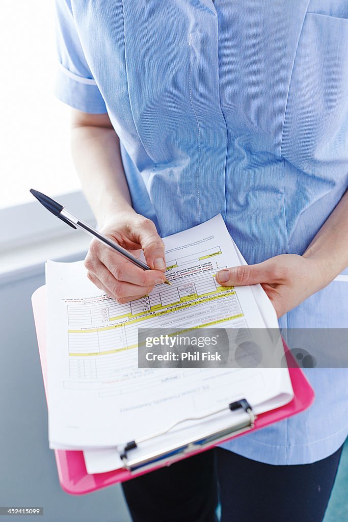 Mid-section of nurse writing paperwork