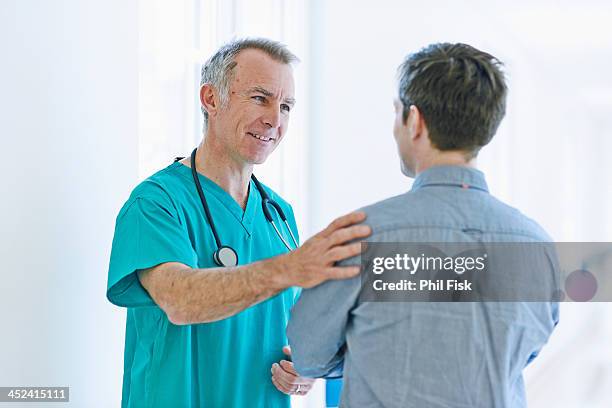 surgeon talking to man - doctor standing stock pictures, royalty-free photos & images