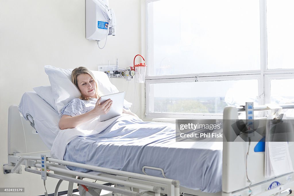 Patient lying on hospital bed using digital tablet