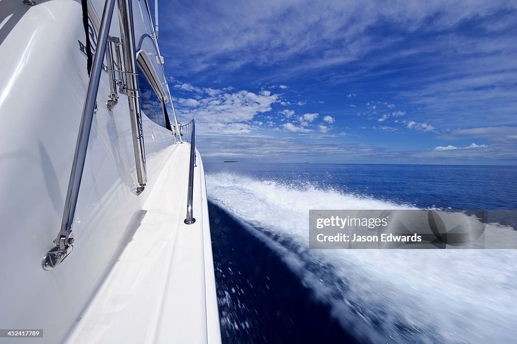A luxury boat ploughs through a calm turquoise ocean in the Pacific.