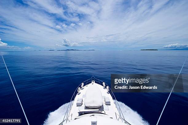 a luxury boat ploughs through a calm turquoise ocean in the pacific. - fiji stockfoto's en -beelden