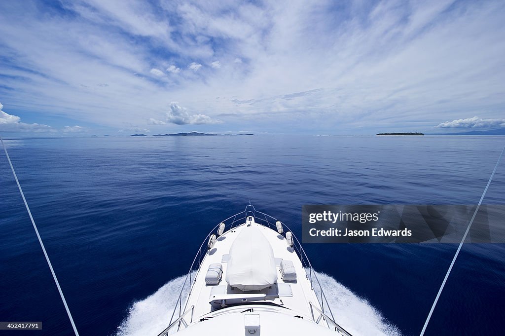 A luxury boat ploughs through a calm turquoise ocean in the Pacific.