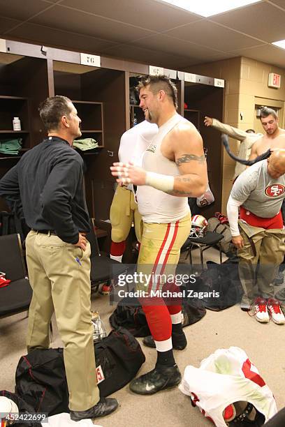 Head Coach Jim Harbaugh of the San Francisco 49ers talks with Alex Boone in the locker room following the game against the Washington Redskins at...