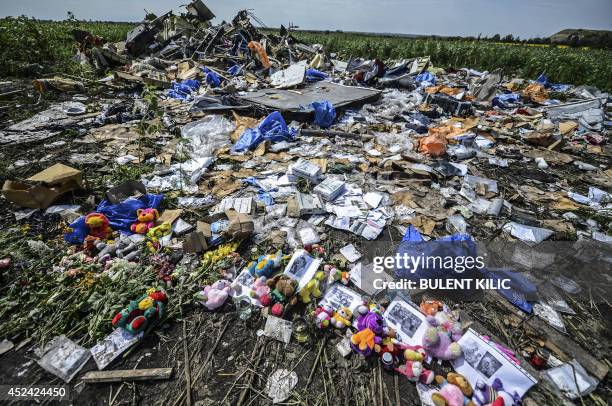 Flowers, soft toys along with pictures are left amongst the wreckage at the site of the crash of a Malaysia Airlines plane carrying 298 people from...