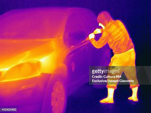 thermal photograph of a burglar breaking into a car - thermal imaging imagens e fotografias de stock