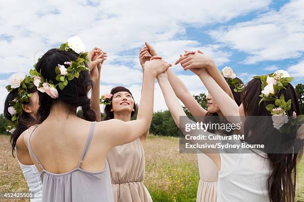 group of women with flowers on their heads, holding hands in circle - cultura orientale photos et images de collection