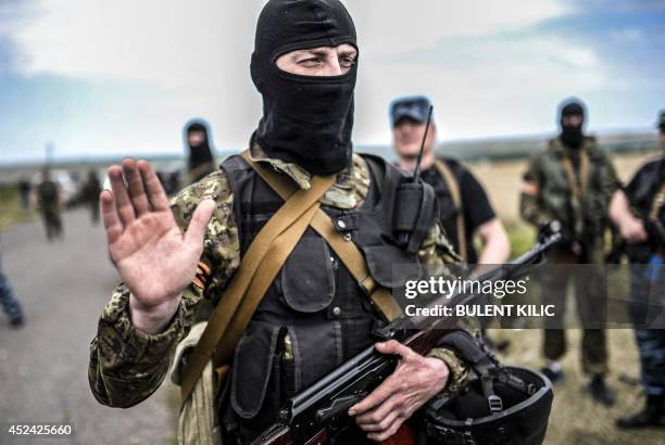 An armed pro-Russian separatists gestures as he blocks the way to the crash site of Malaysia Airlines Flight MH17, near the village of Grabove, in...