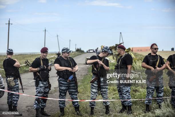 Armed pro-Russian separatists stand guard in front of the crash site of Malaysia Airlines Flight MH17, near the village of Grabove, in the region of...