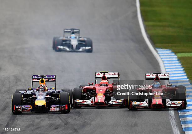 Sebastian Vettel of Germany and Infiniti Red Bull Racing drives next to Kimi Raikkonen of Finland and Ferrari and Fernando Alonso of Spain and...