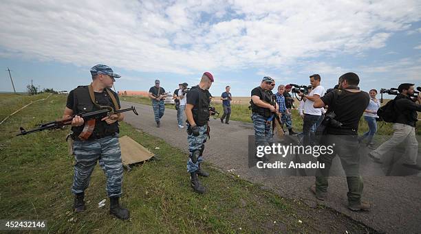 Pro-Russian separatists stand guard at the site of crash as representative from monitoring group of Organization for Security and Cooperation in...